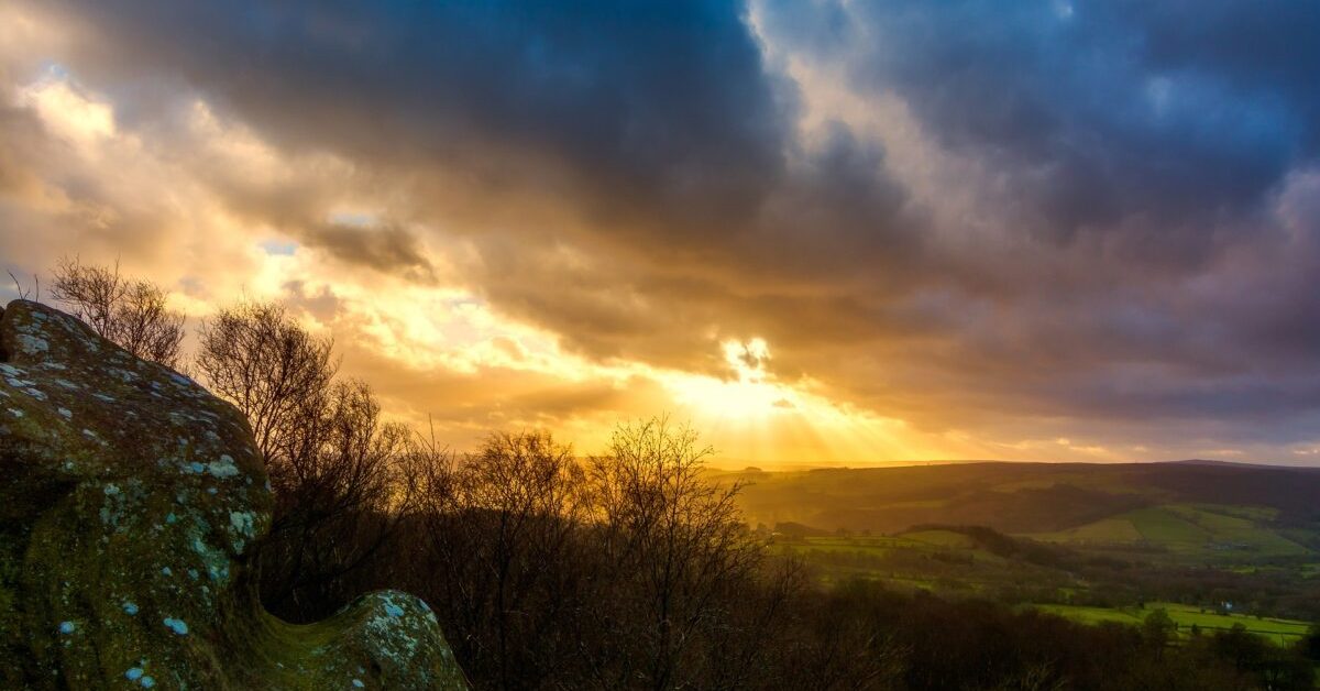 Sun breaking through clouds over moor